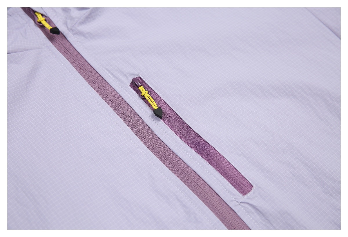 Close-up of a lavender grid-patterned garment with plum zippers and bright yellow-and-black zipper pulls.