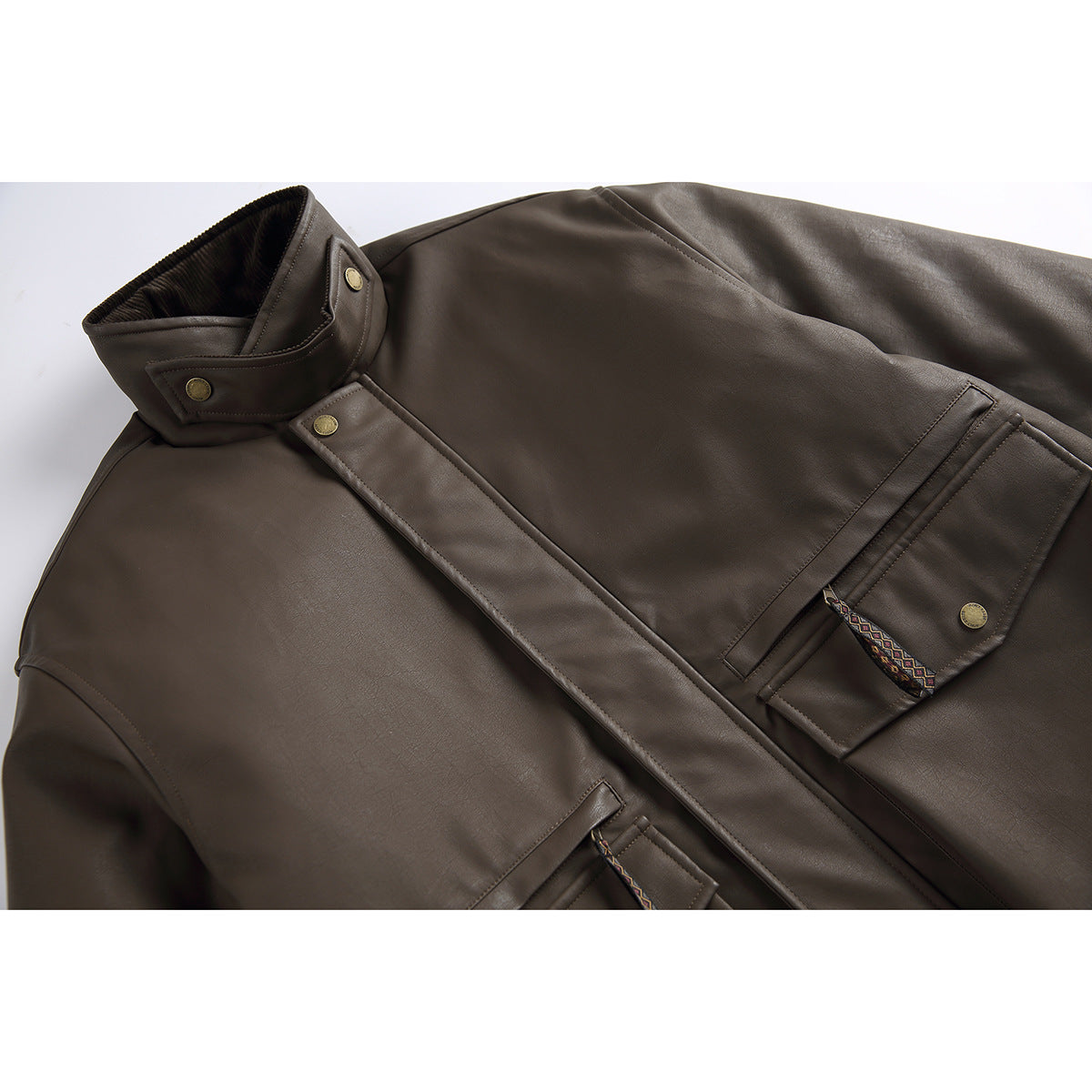 Close-up of a dark brown jacket showing its high collar, snap-button placket, and flap pockets with patterned pulls.