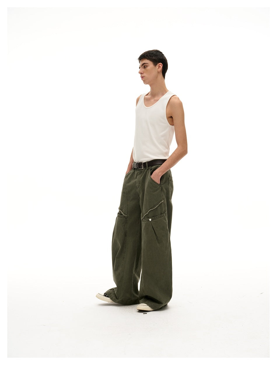 Side-angle view of a model wearing dark olive wide-leg pants with layered knee panels and a white tank top.
