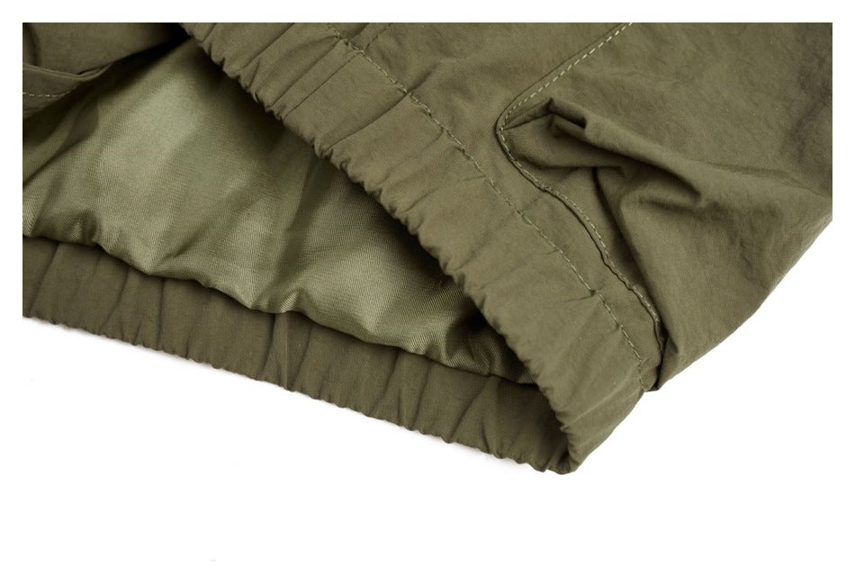 Close-up of the olive jacket's gathered hem, inner lining and side seam.