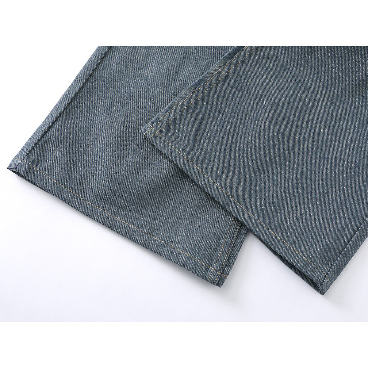 Close-up of two blue-gray jean hems with tan stitching.