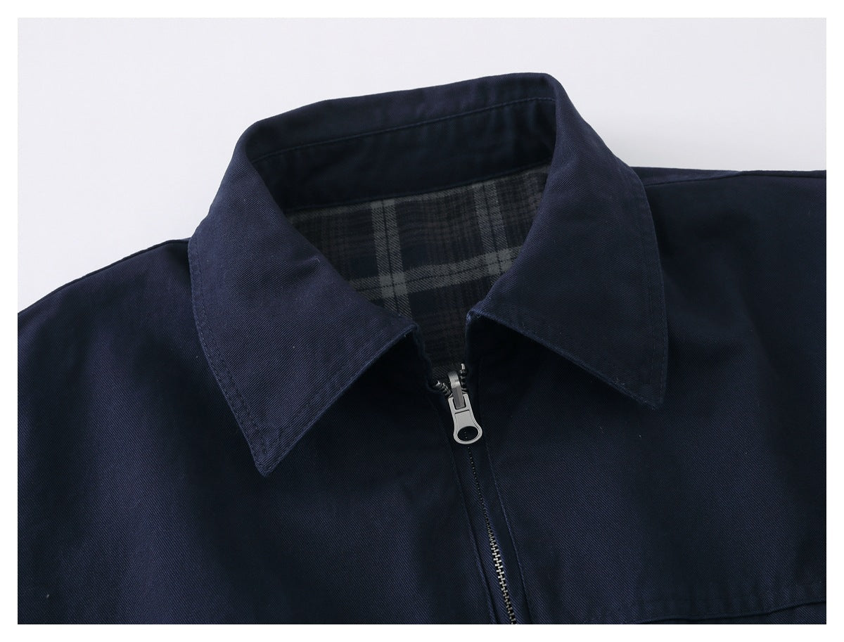 Close-up of a dark navy jacket's pointed collar, front zipper, and gray plaid lining.