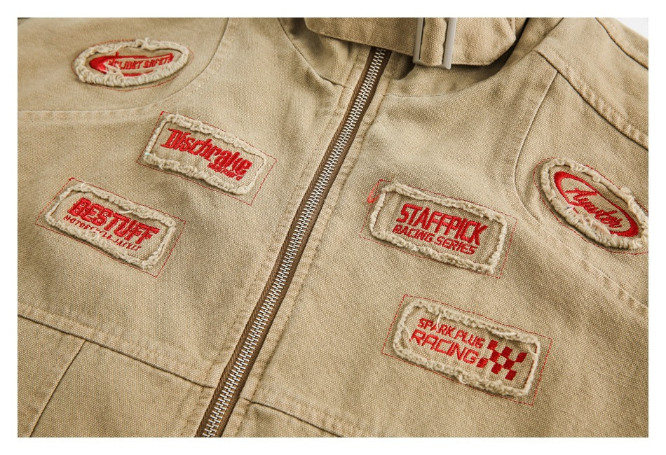 Close-up of the tan jacket front, showing several red-and-cream embroidered patches and the zipper.