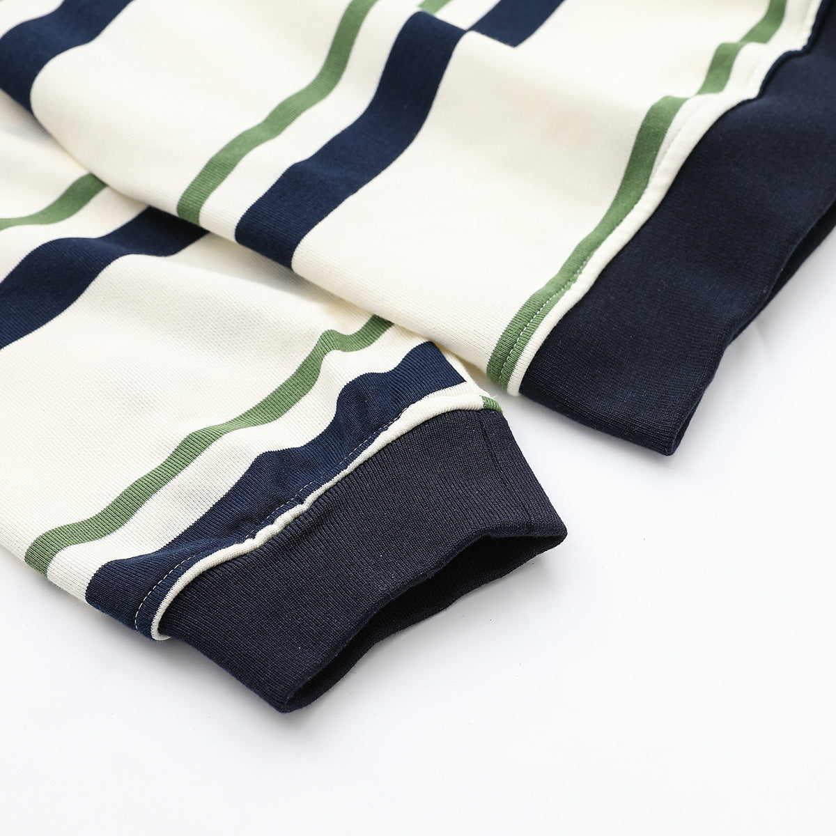 Close-up of ivory fabric with navy and green stripes beside a dark ribbed cuff.