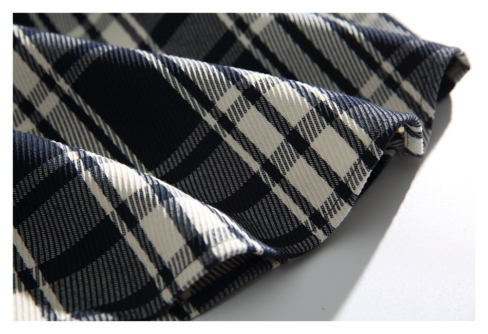 Close-up of a folded edge of the navy, black, and cream plaid shirt.