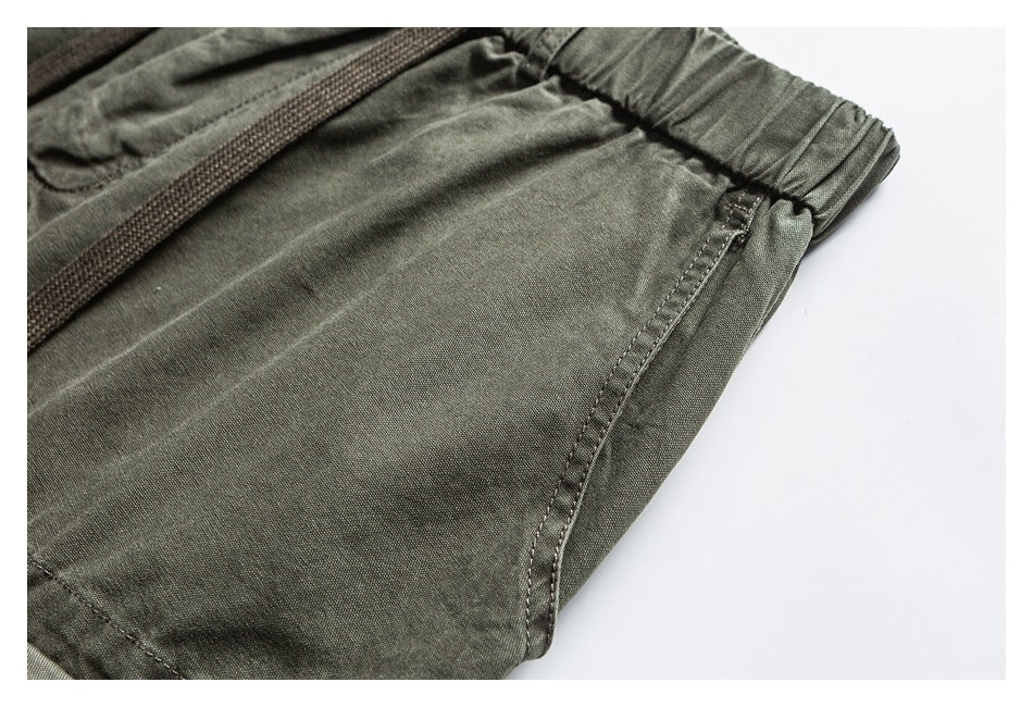 Close-up of olive pants showing the elastic waistband, drawcord, and side seam.