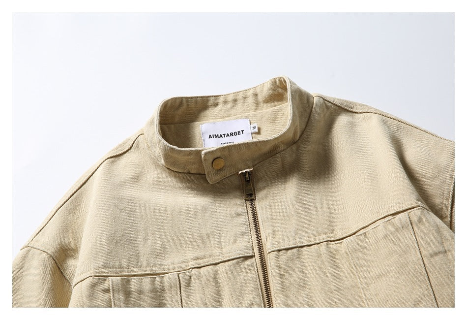 Close-up of a sand-colored jacket’s stand collar, snap closure, zipper, and sewn neck label.