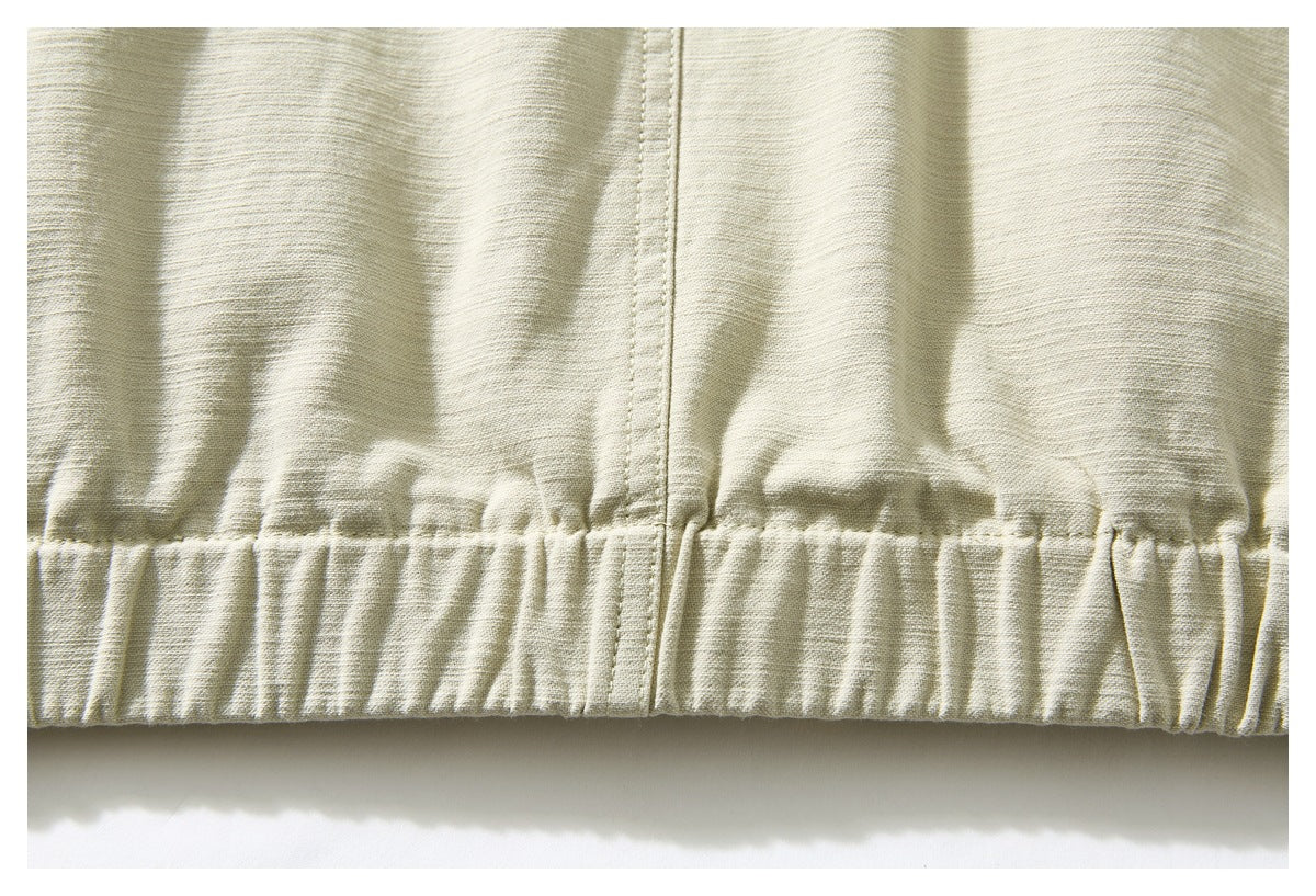 Close-up of the pale beige jacket's gathered elastic hem and central seam.