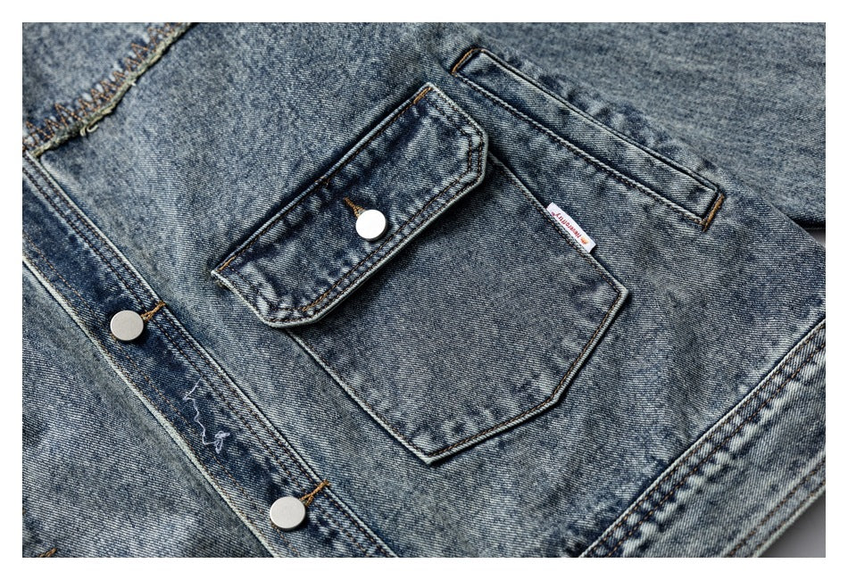 Close-up of a denim jacket chest pocket with a buttoned flap and silver snap-front buttons.