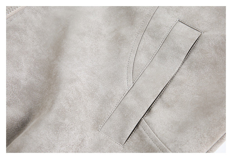 Close-up of a rectangular welt pocket and stitching on a light gray jacket.