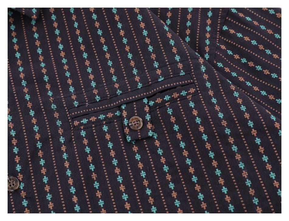 Close-up of the patterned shirt's chest pocket, buttoned flap, stitching, and teal and brown motifs.