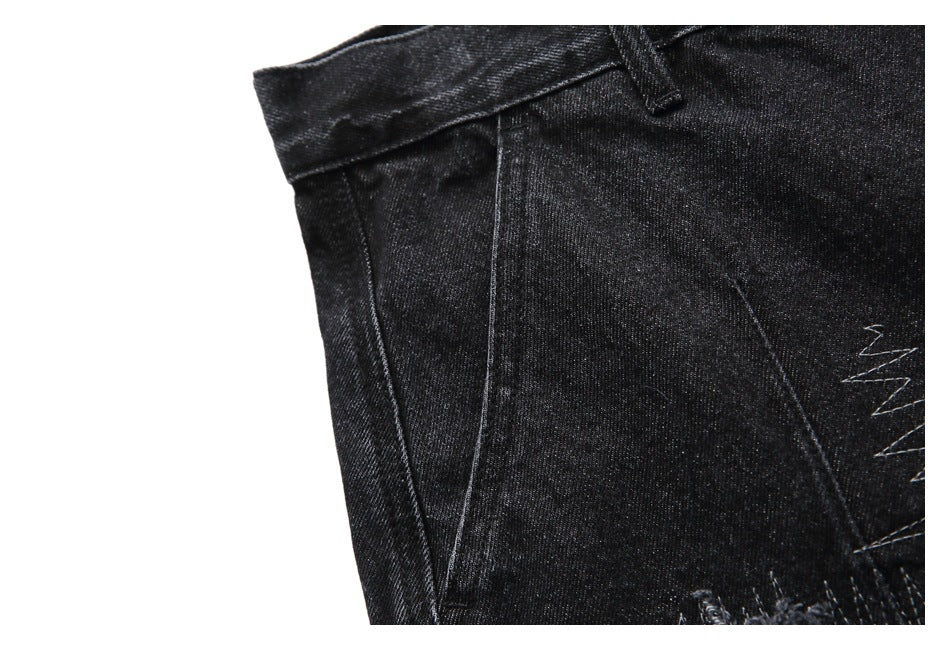 Close-up of black denim shorts showing a side seam, waistband, and partial distressed stitching.