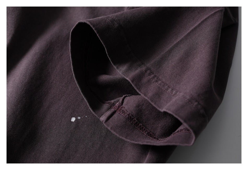 Close-up of the dark plum shirt's short sleeve opening, showing the hem stitching and inside seam.