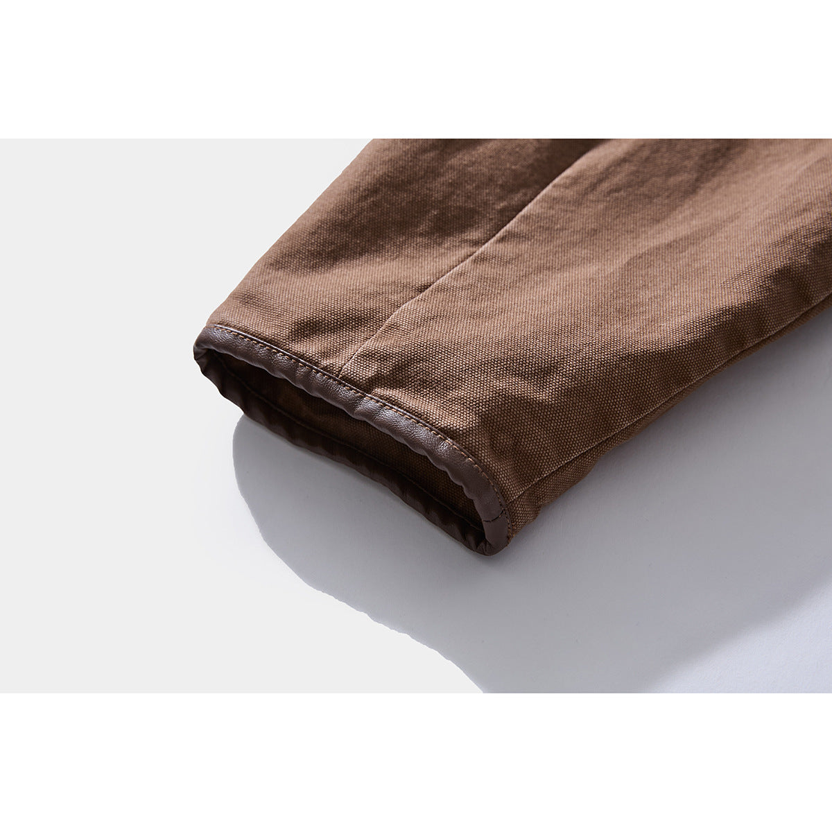 Close-up of a brown jacket sleeve cuff with dark trim and textured fabric.
