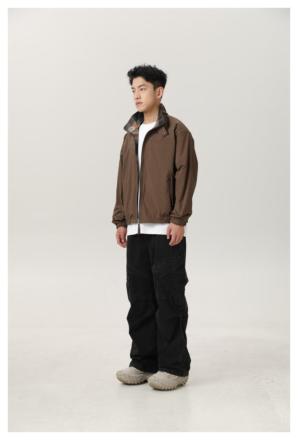 Model wearing the brown zip jacket with a white tee and black cargo pants, plaid lining visible at the collar