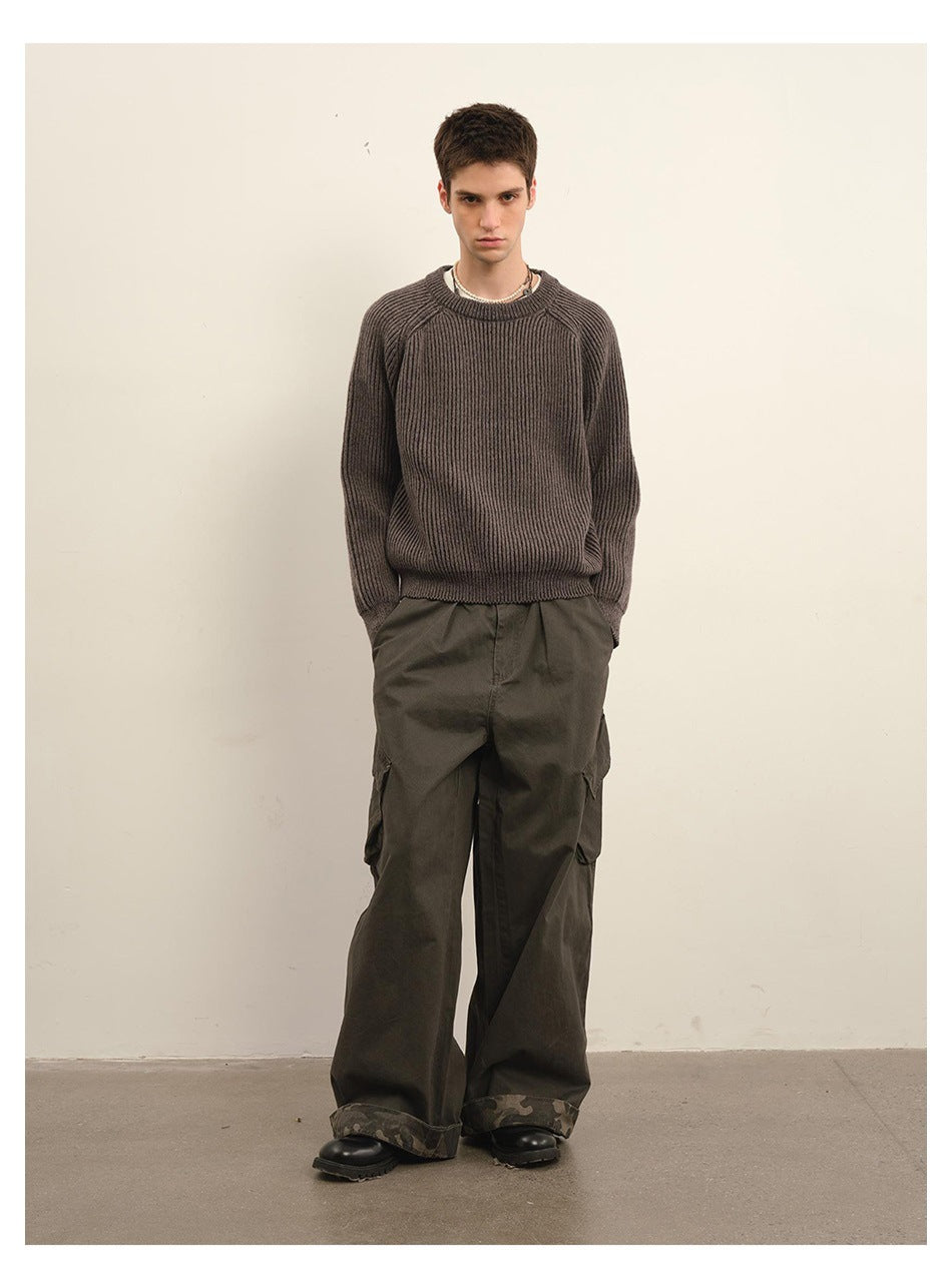Model standing in a dark gray rib-knit crewneck sweater with olive wide-leg cargo pants