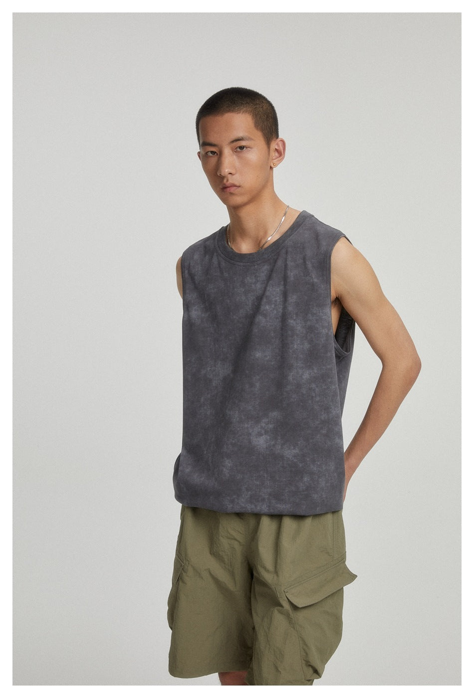 Model wearing a charcoal mottled sleeveless crewneck top with olive cargo shorts, shown at an angle.