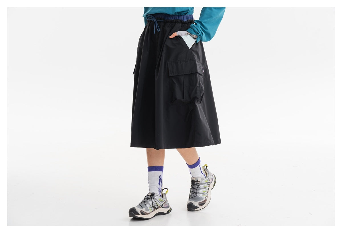 Rear view of a black knee-length cargo skirt with an elastic drawstring waist and large side pockets, worn by a model.