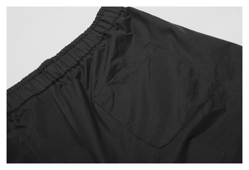 Close-up of a black garment's elastic waistband and stitched patch pocket.
