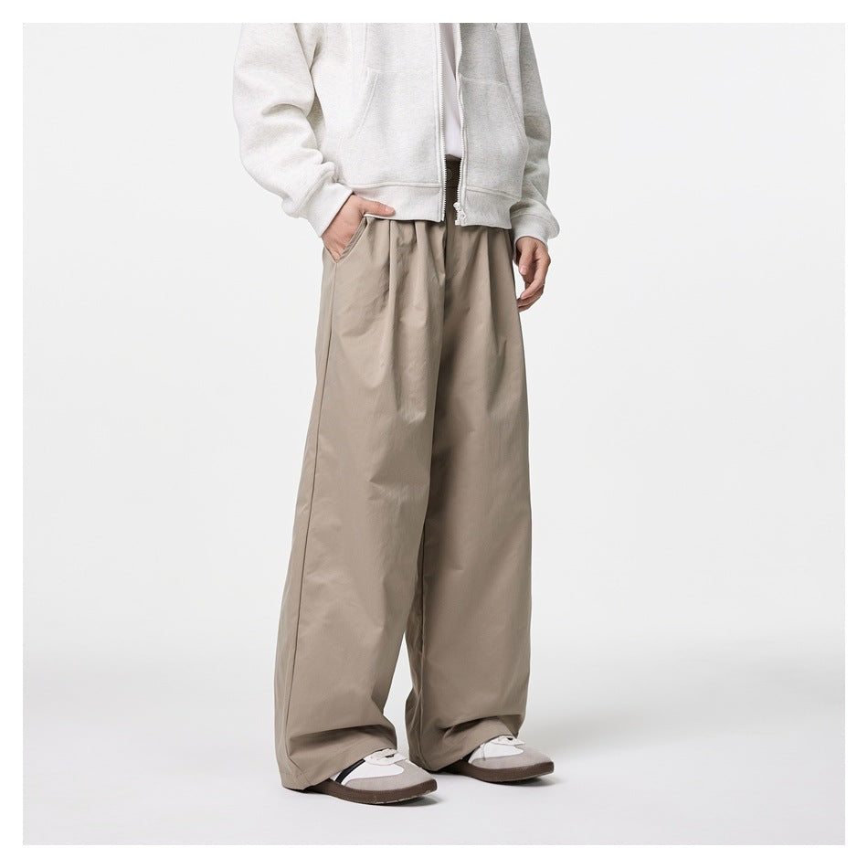 Angled front view of a model wearing loose taupe wide-leg trousers with side pockets.