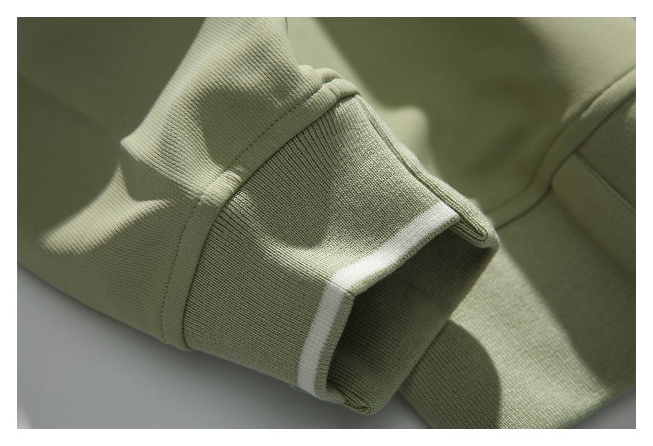 Close-up of a sage-green ribbed sweatshirt cuff with a narrow white stripe at the edge.