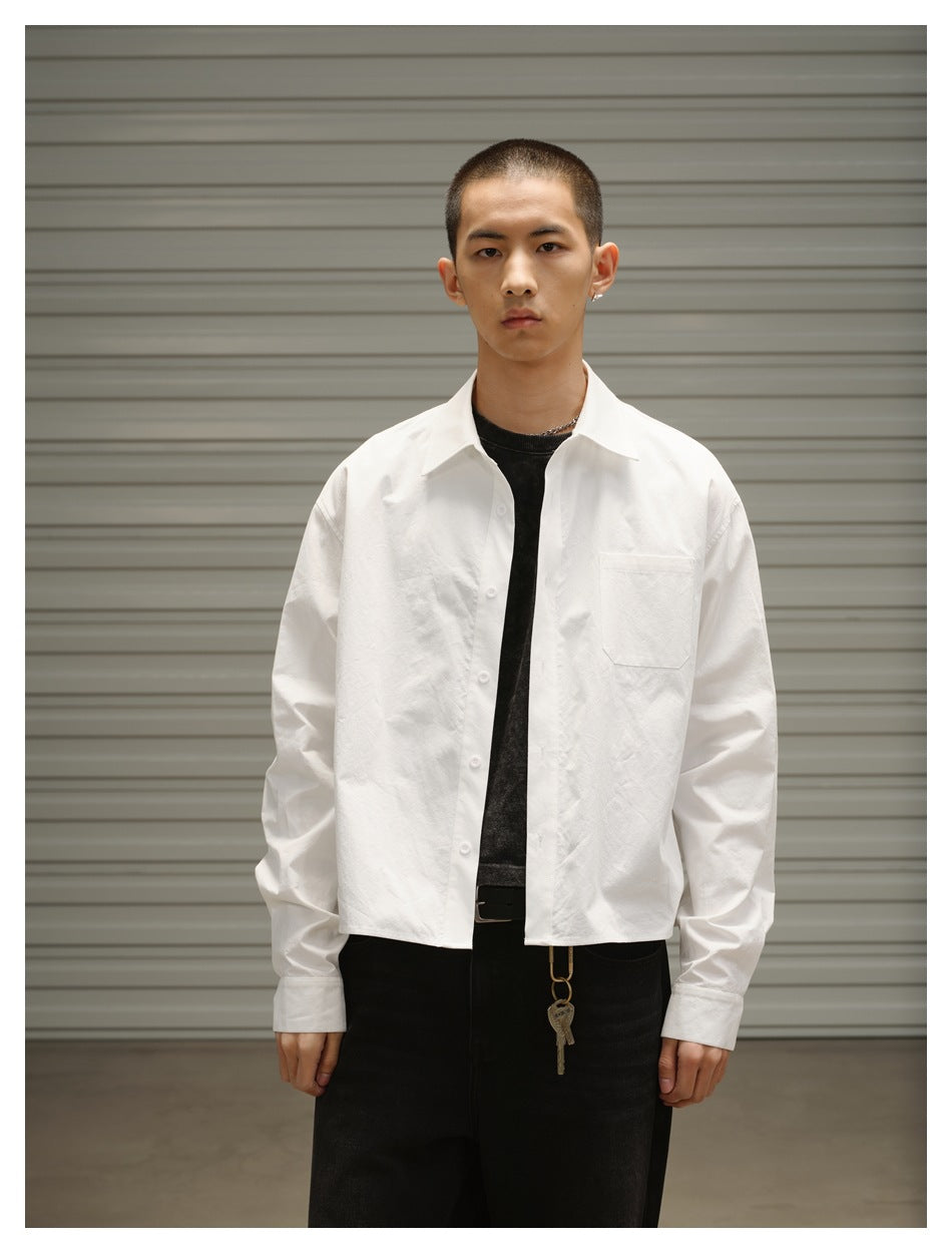 Front view of a model wearing a white long-sleeve button-up shirt with a chest pocket over a black tee.