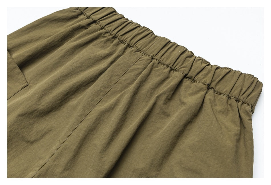 Close-up of olive-khaki pants with a gathered elastic waistband and visible stitching.