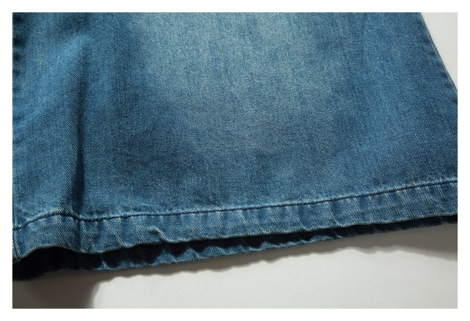 Close-up of a stitched hem on blue denim bottoms.