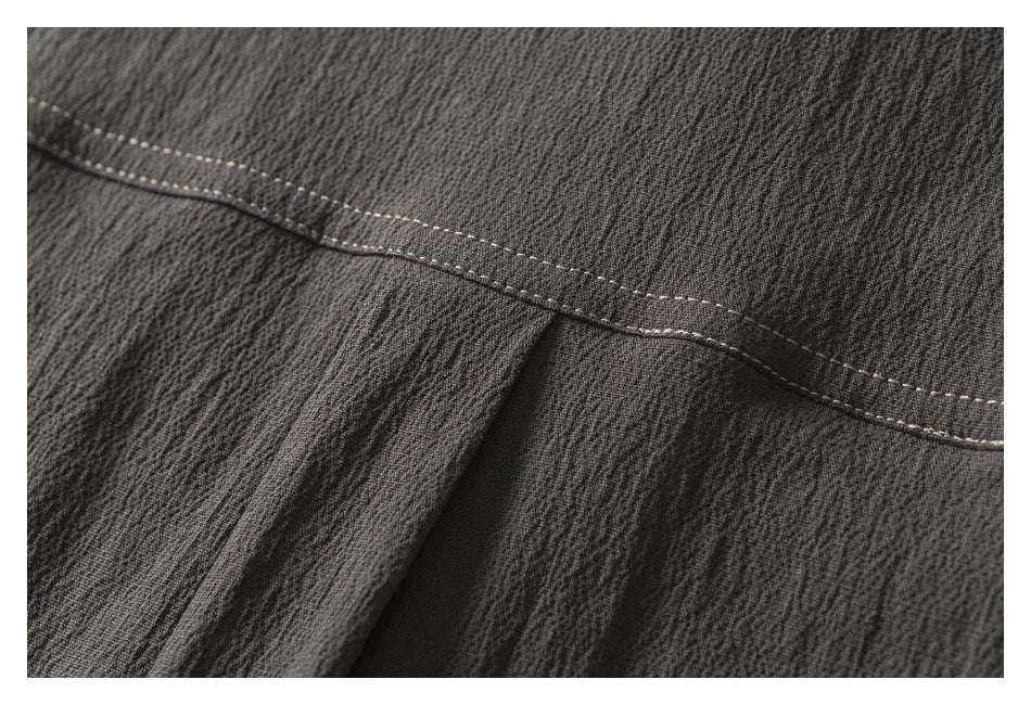 Close-up of a stitched seam and folded section of dark charcoal garment fabric.