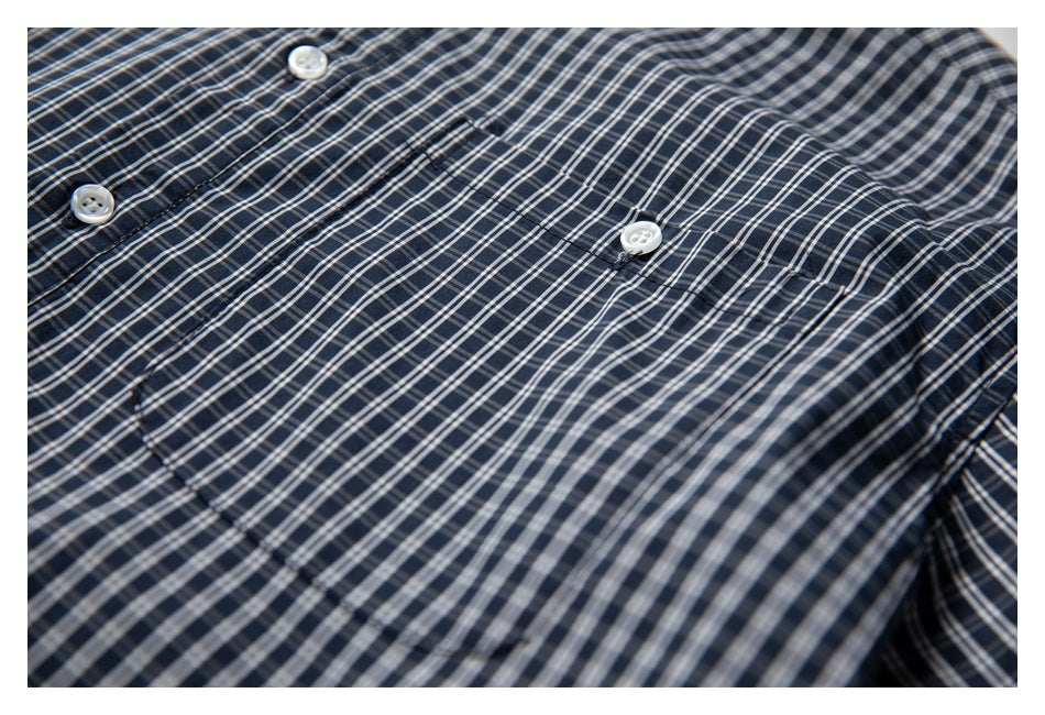 Close-up of a navy plaid shirt pocket and button against the check pattern.