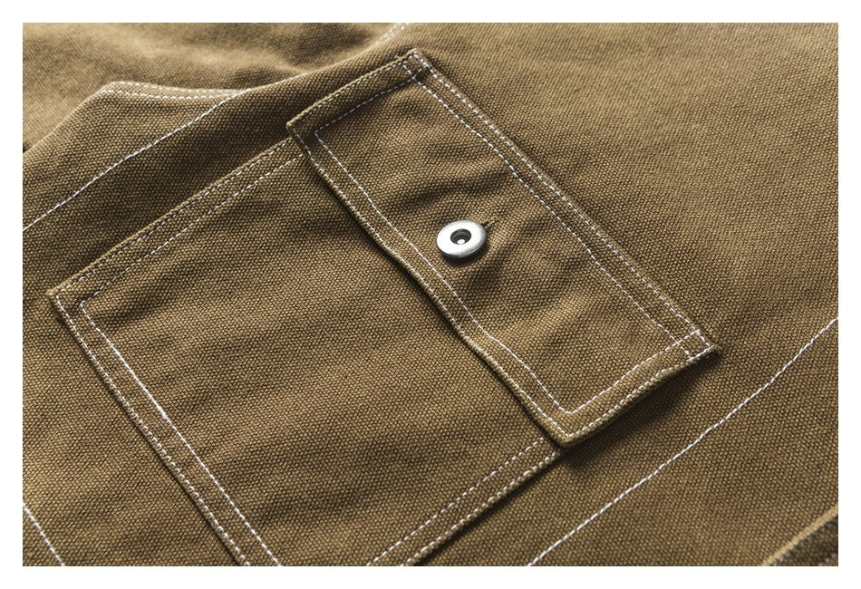Close-up of a buttoned flap pocket and contrast stitching on the brown jacket.