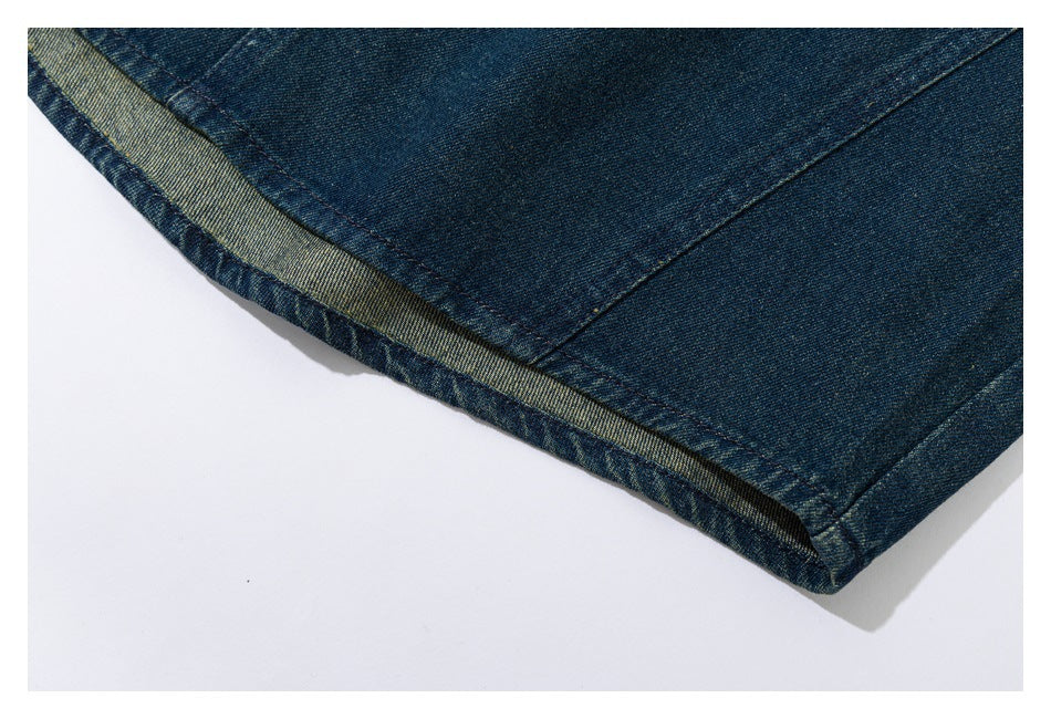 Close-up of a dark blue denim garment hem, showing the folded edge and stitching.
