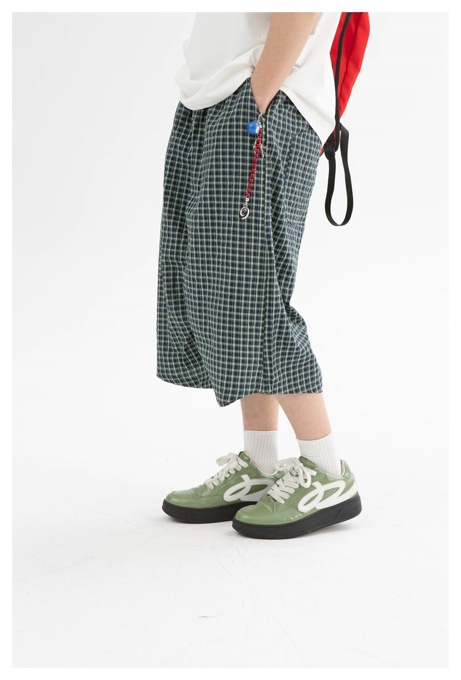 Close view of navy-and-green plaid shorts worn with a white shirt, showing the side pocket and hem.