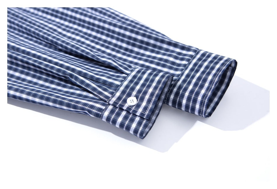 Close-up of a navy, white, and gray plaid shirt sleeve with a buttoned cuff.