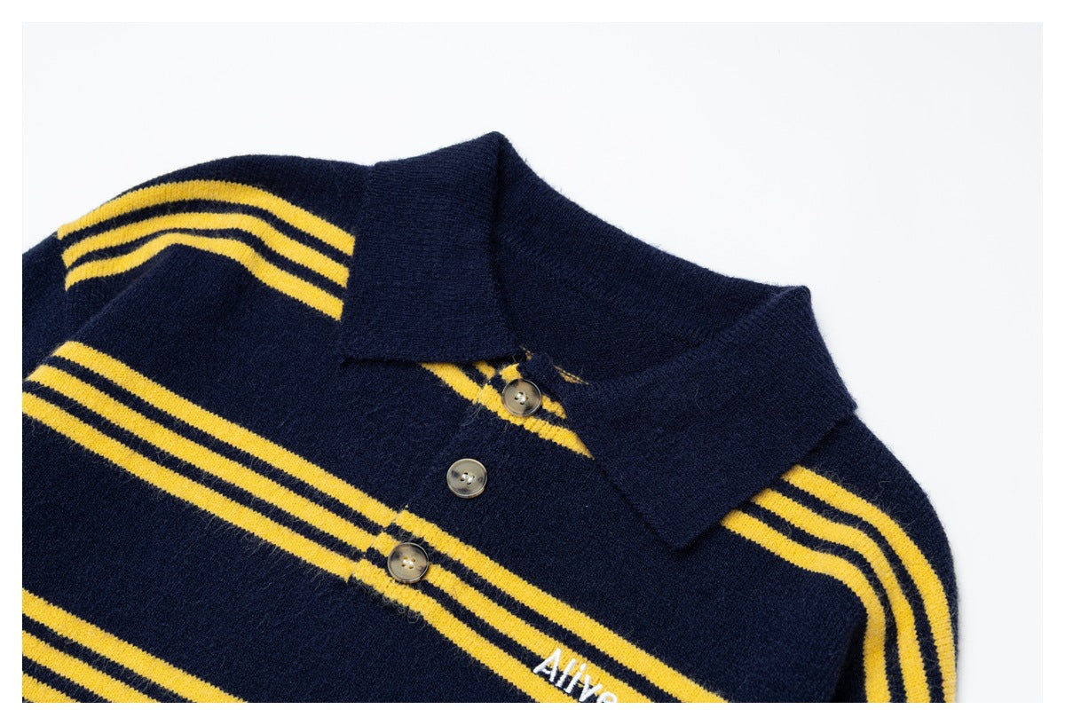 Close-up of the collar, buttons and yellow stripes on a navy knit polo sweater, with white chest embroidery.