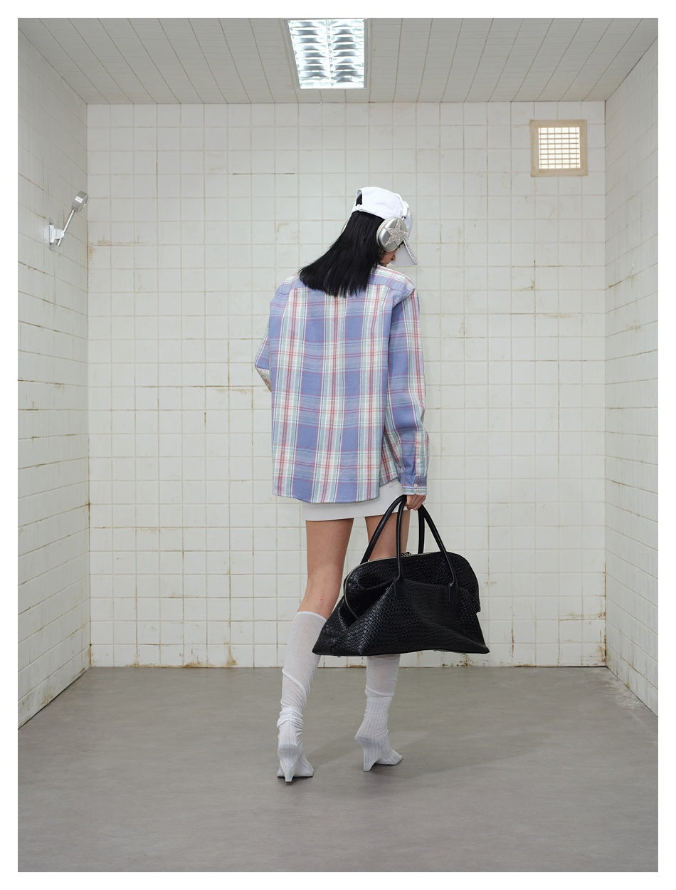 Back view of model wearing the plaid shirt with a white cap, white skirt and black woven bag