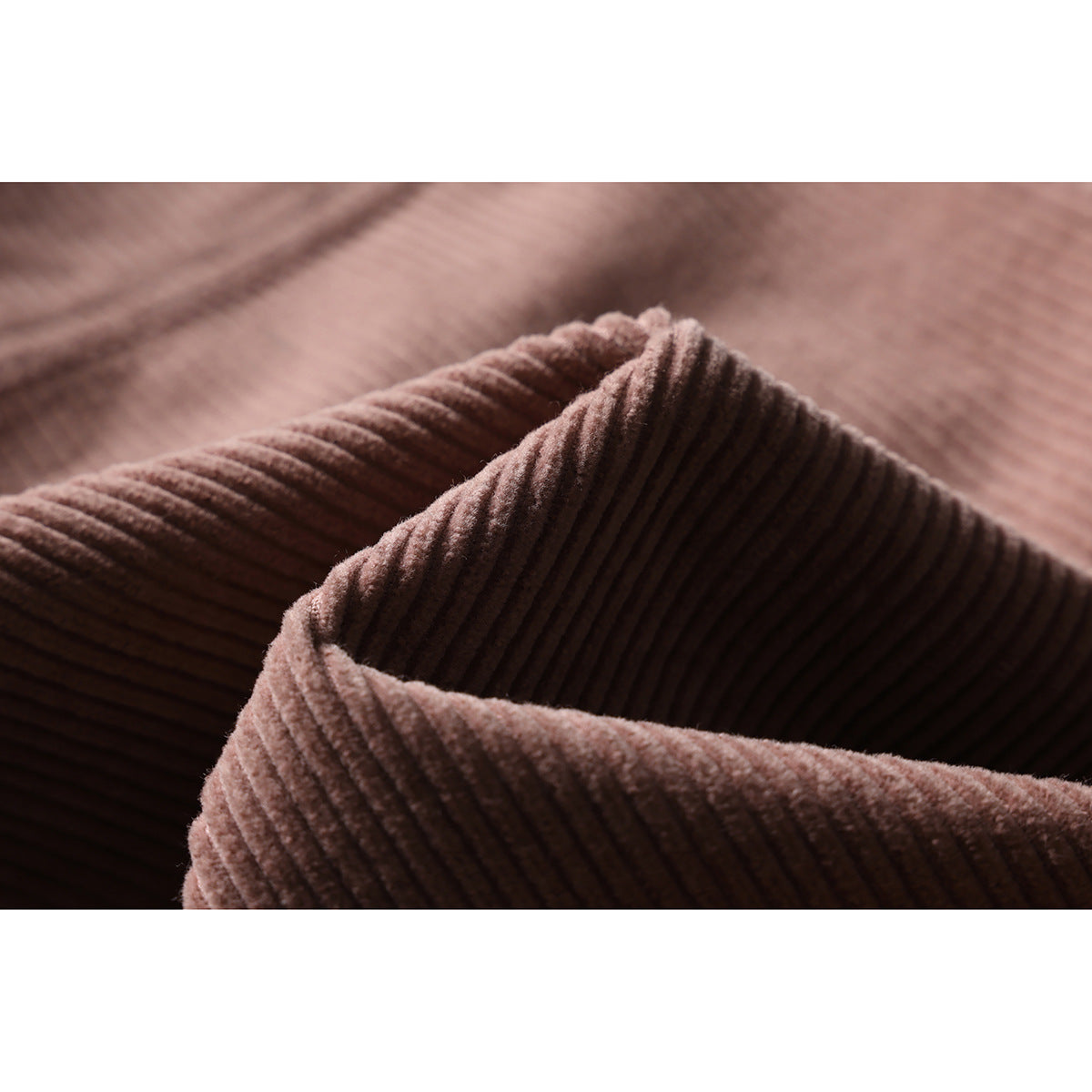 Close-up of a folded edge of dusty rose ribbed fabric, highlighting its raised vertical texture.