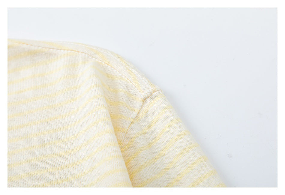 Close-up of a cream knit garment with pale yellow stripes and a curved shoulder seam.