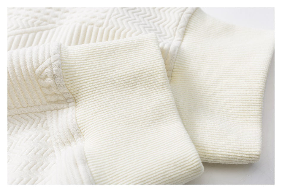 Close-up of cream garment showing two wide ribbed cuffs against textured quilted fabric.