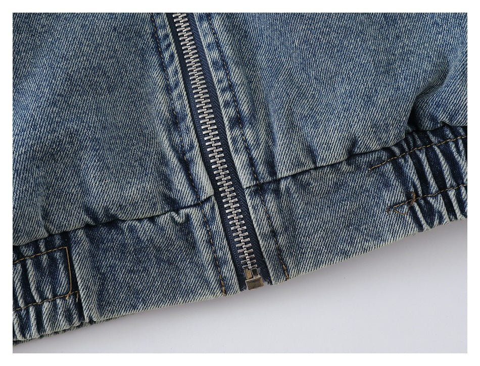 Close-up of the jacket's central zipper and gathered elastic hem in blue washed denim.