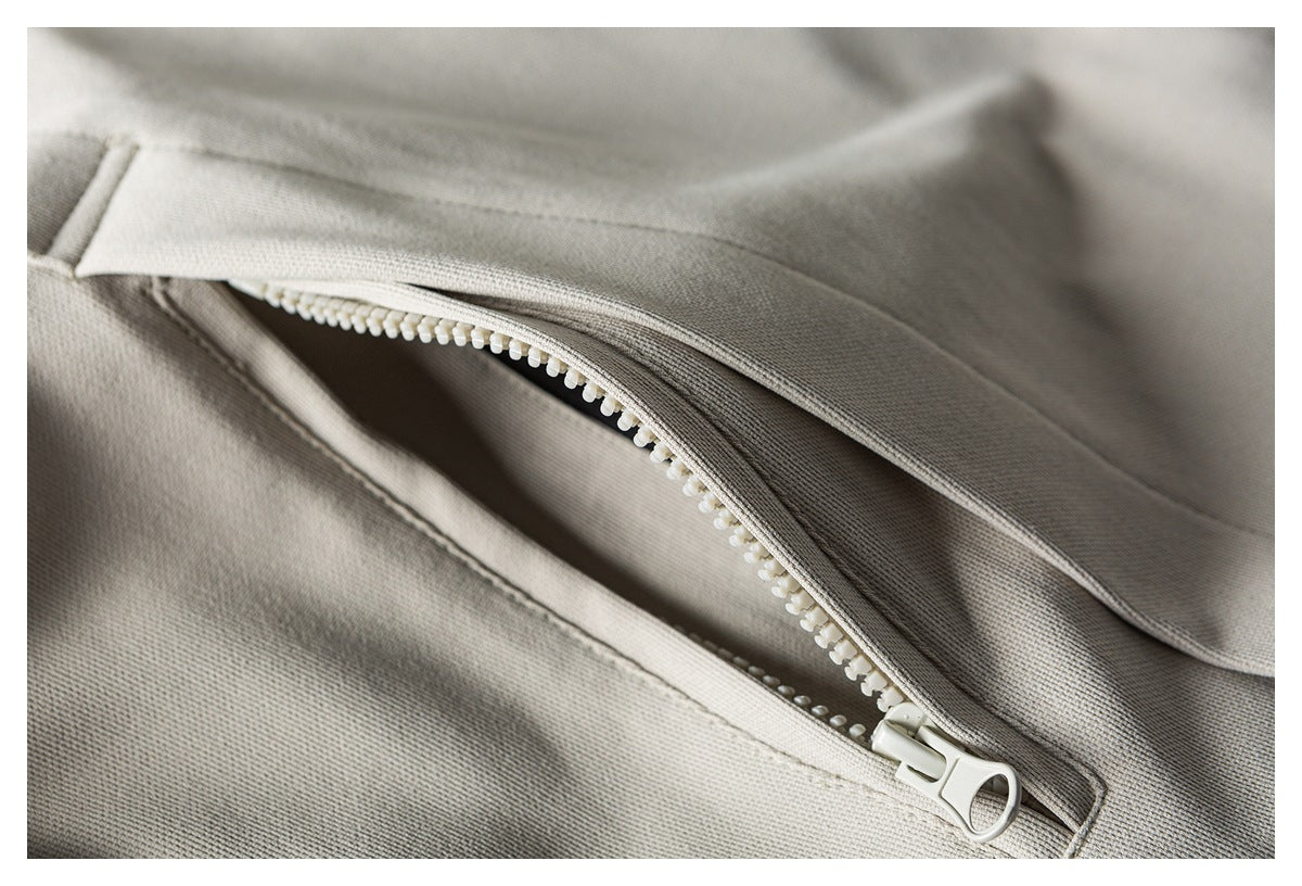 Close-up of a chunky white zipper on light taupe fabric.