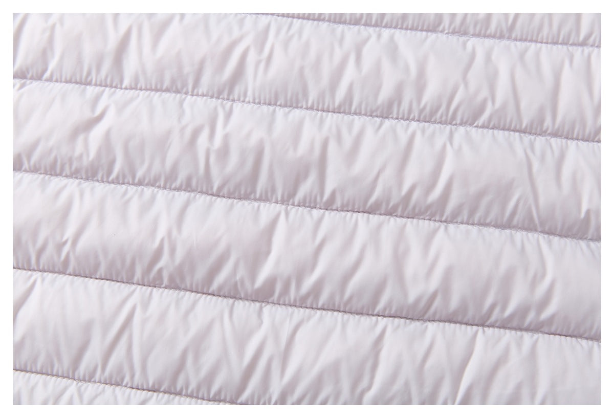 Close-up showing the horizontal stitched channels and smooth pale lavender fabric of a quilted jacket.