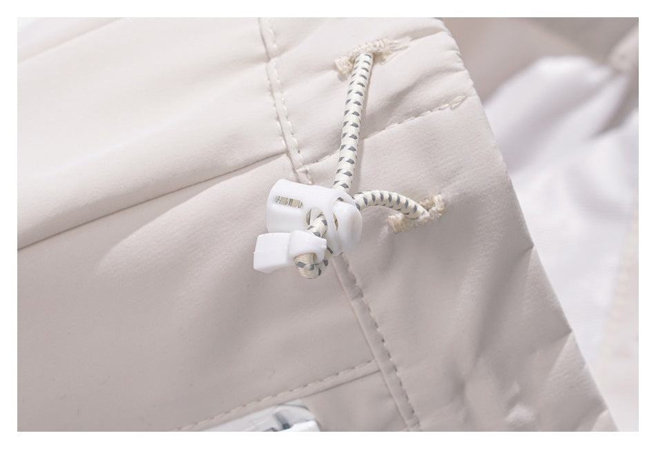 Close-up of an off-white garment with a patterned drawcord and white plastic toggle.