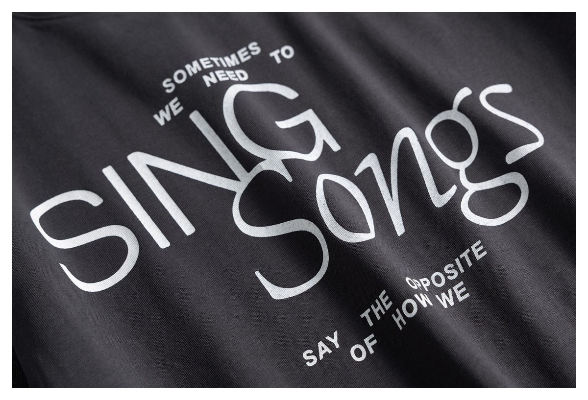 Close-up of white English lettering printed across the charcoal T-shirt.