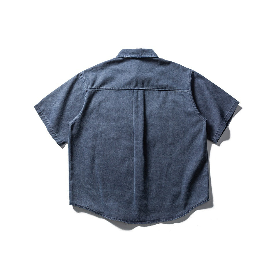 Back view of a dark blue short-sleeve button-up shirt with a yoke and center pleat.
