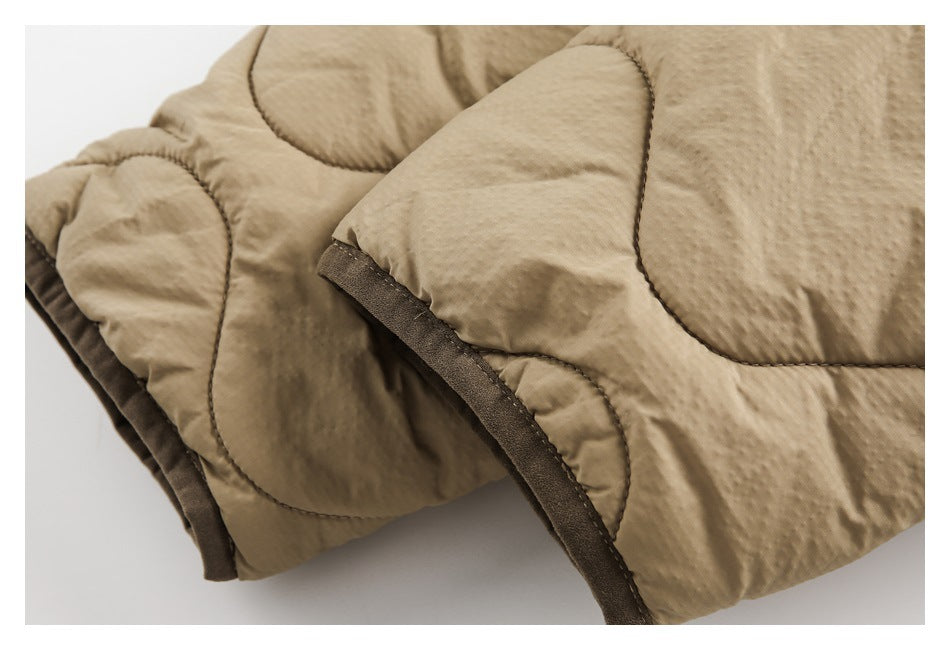 Close-up of tan quilted outerwear showing padded panels and dark brown edging.