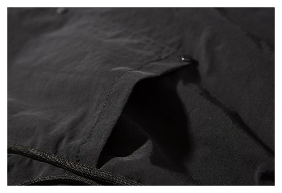 Close-up showing the opening and snap closure of a pocket on black shorts.