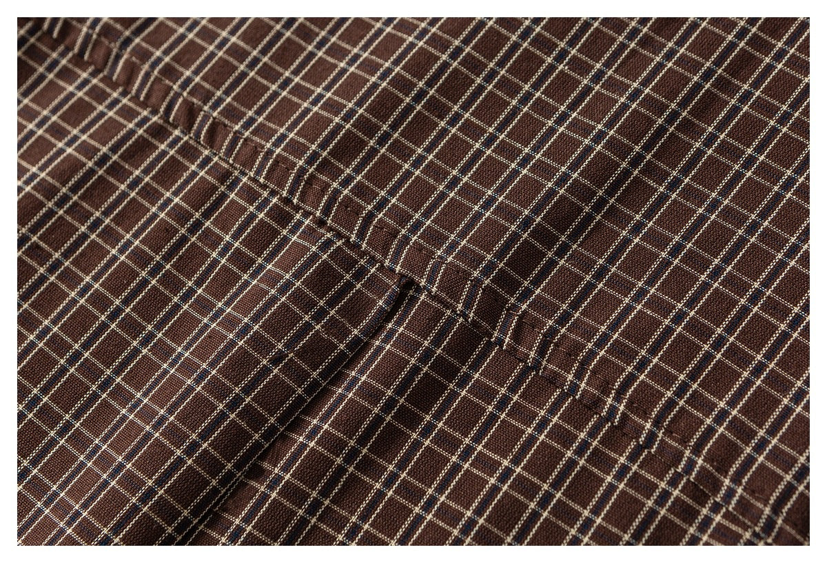Close-up of brown plaid fabric with cream and blue grid lines and a stitched seam.