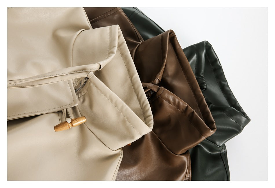 Close view of cream, brown, and dark-green jackets layered together, showing their toggle closures and pockets.