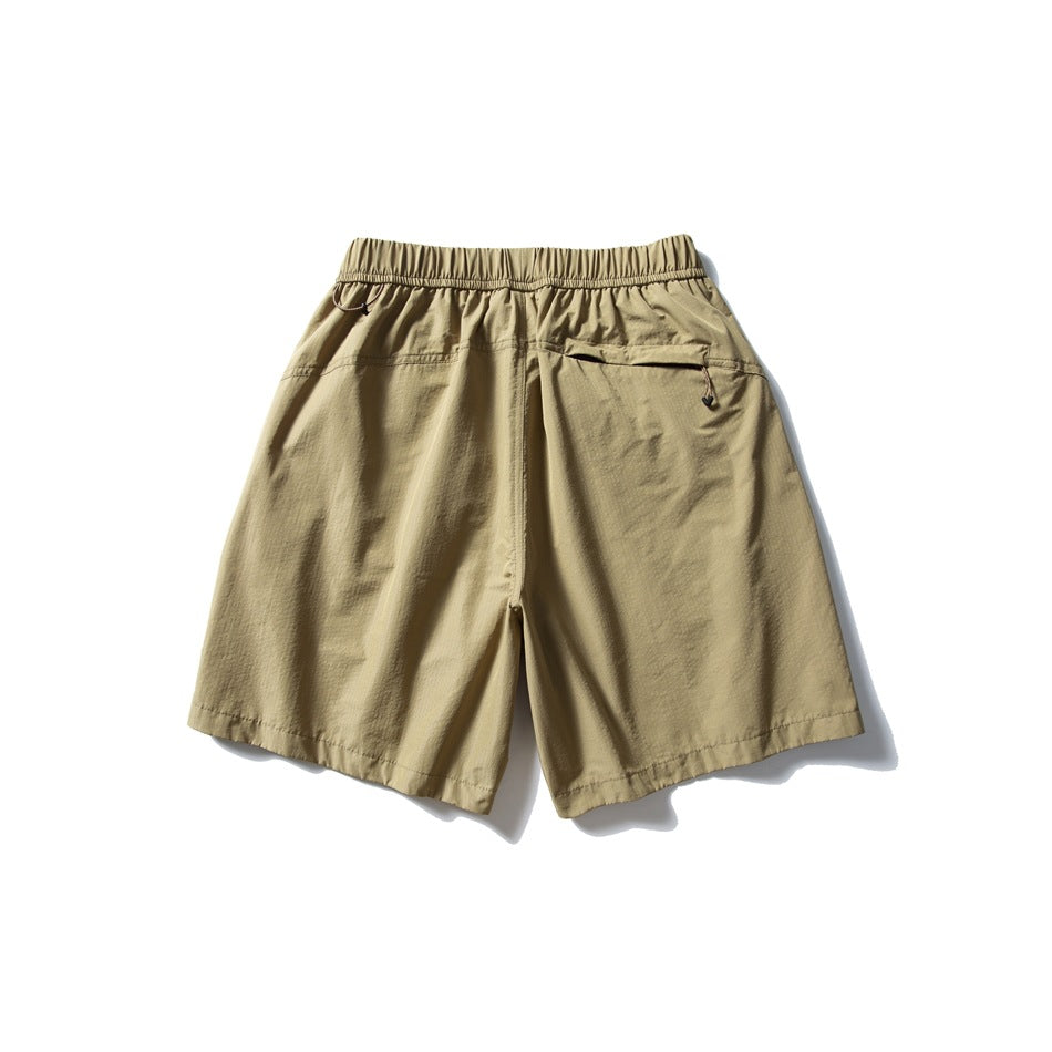 Back view of khaki shorts with an elastic waistband and a zip pocket.